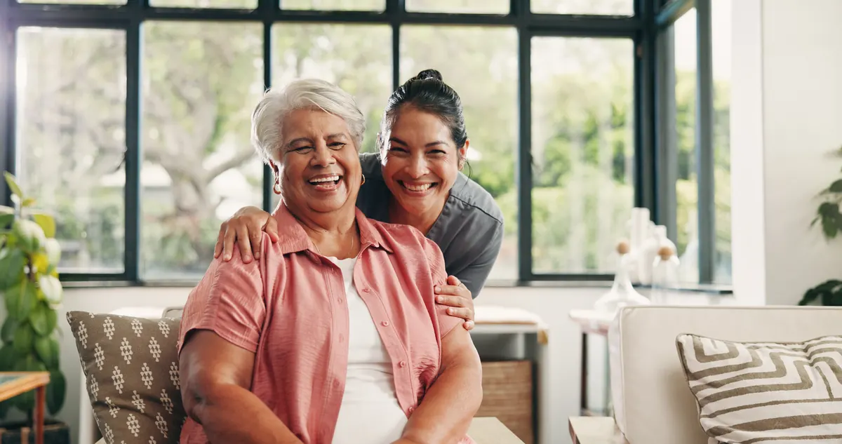 A caregiver embracing an older woman at home