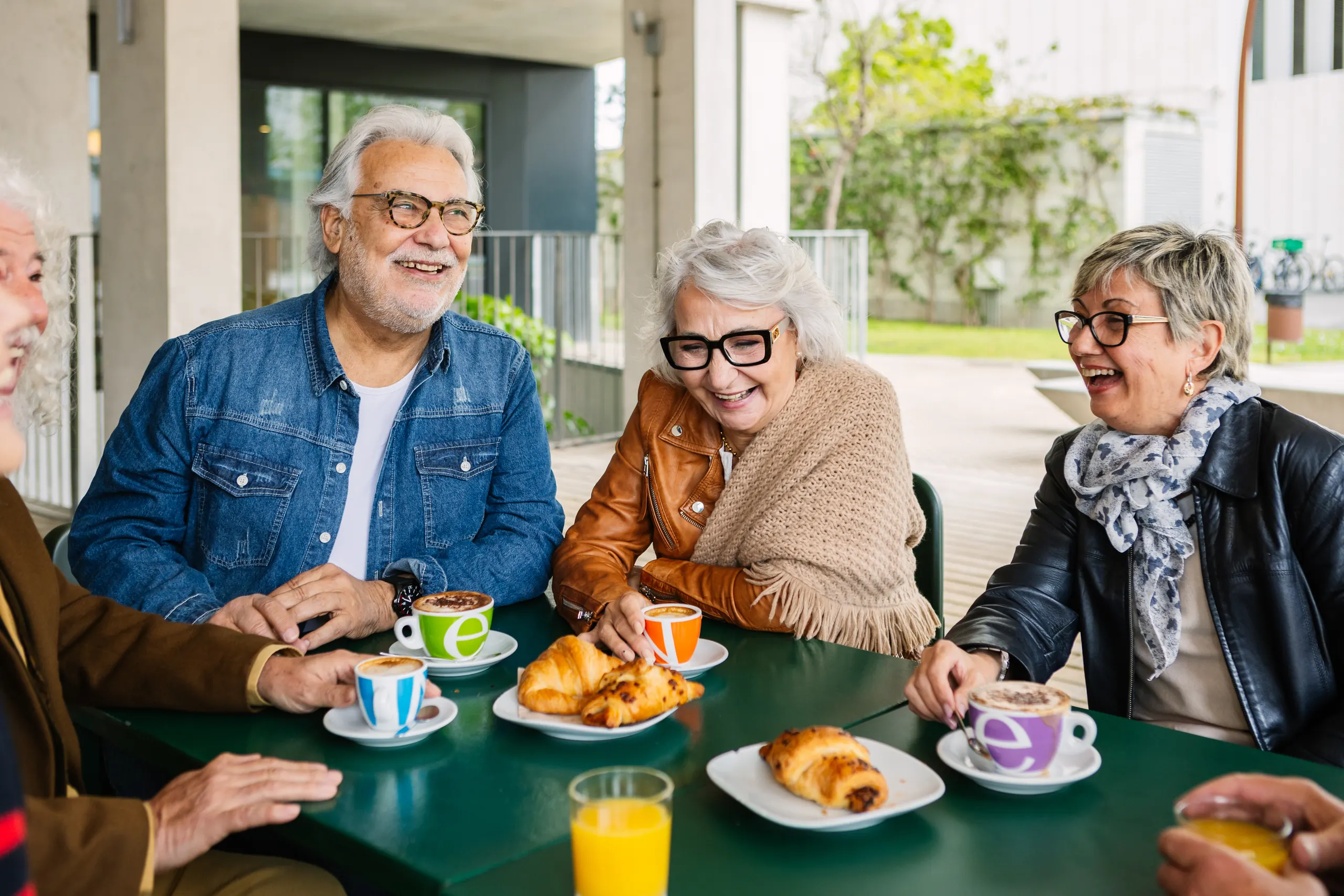 Senior friends laughing over breakfast on a patio