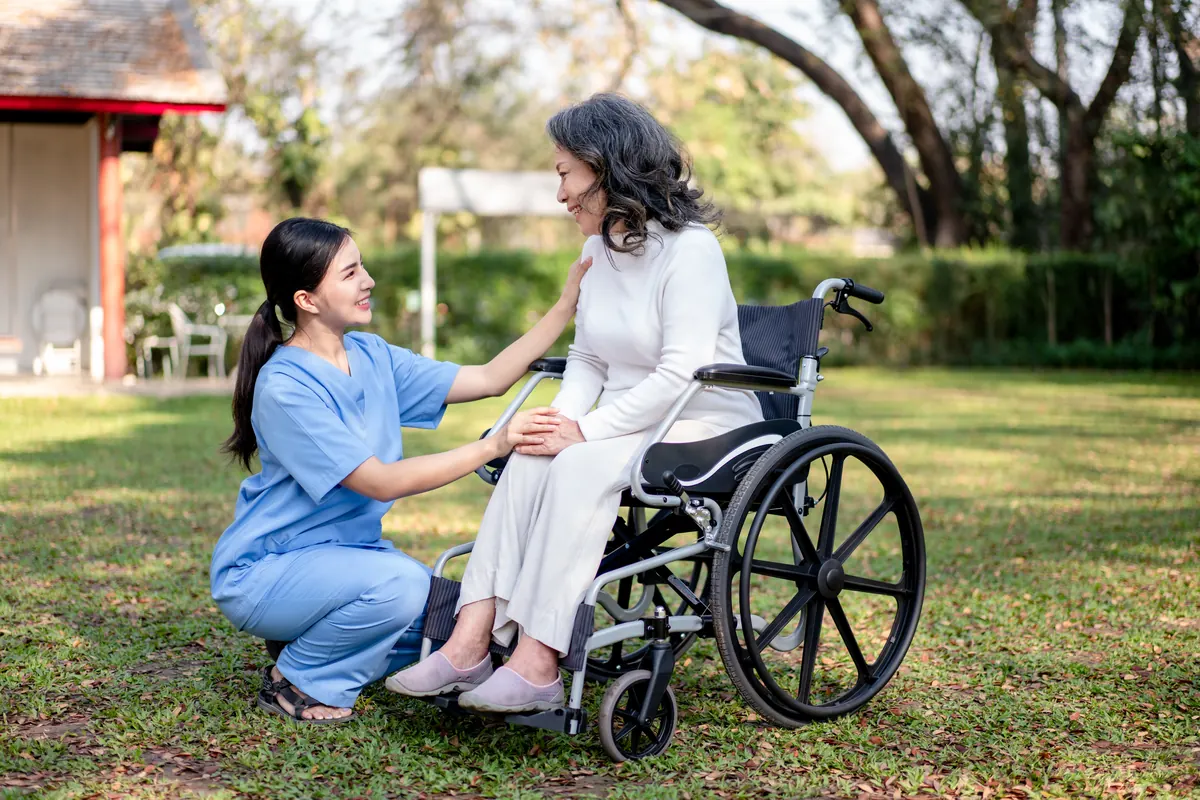 A caregiver kneeling beside a smiling resident in a garden