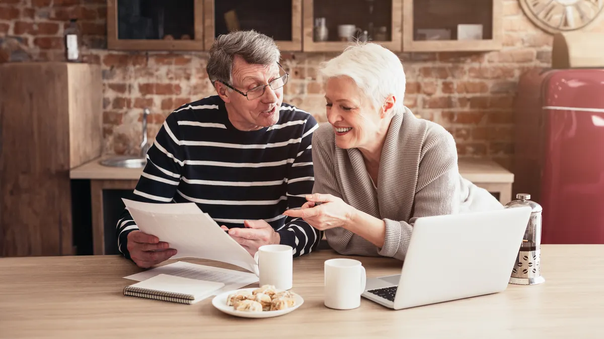 An older couple reviewing paperwork together at the kitchen table