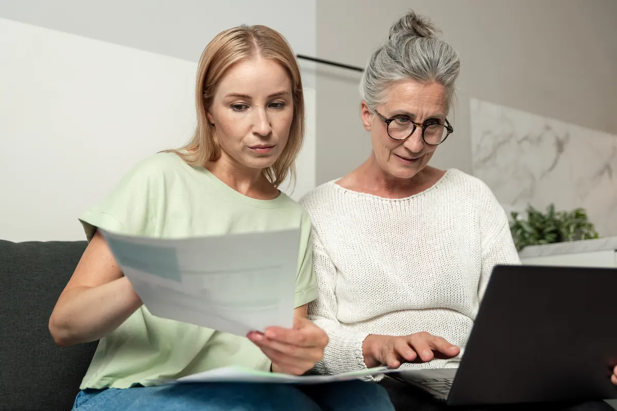 An adult daughter helping her senior mother with documents